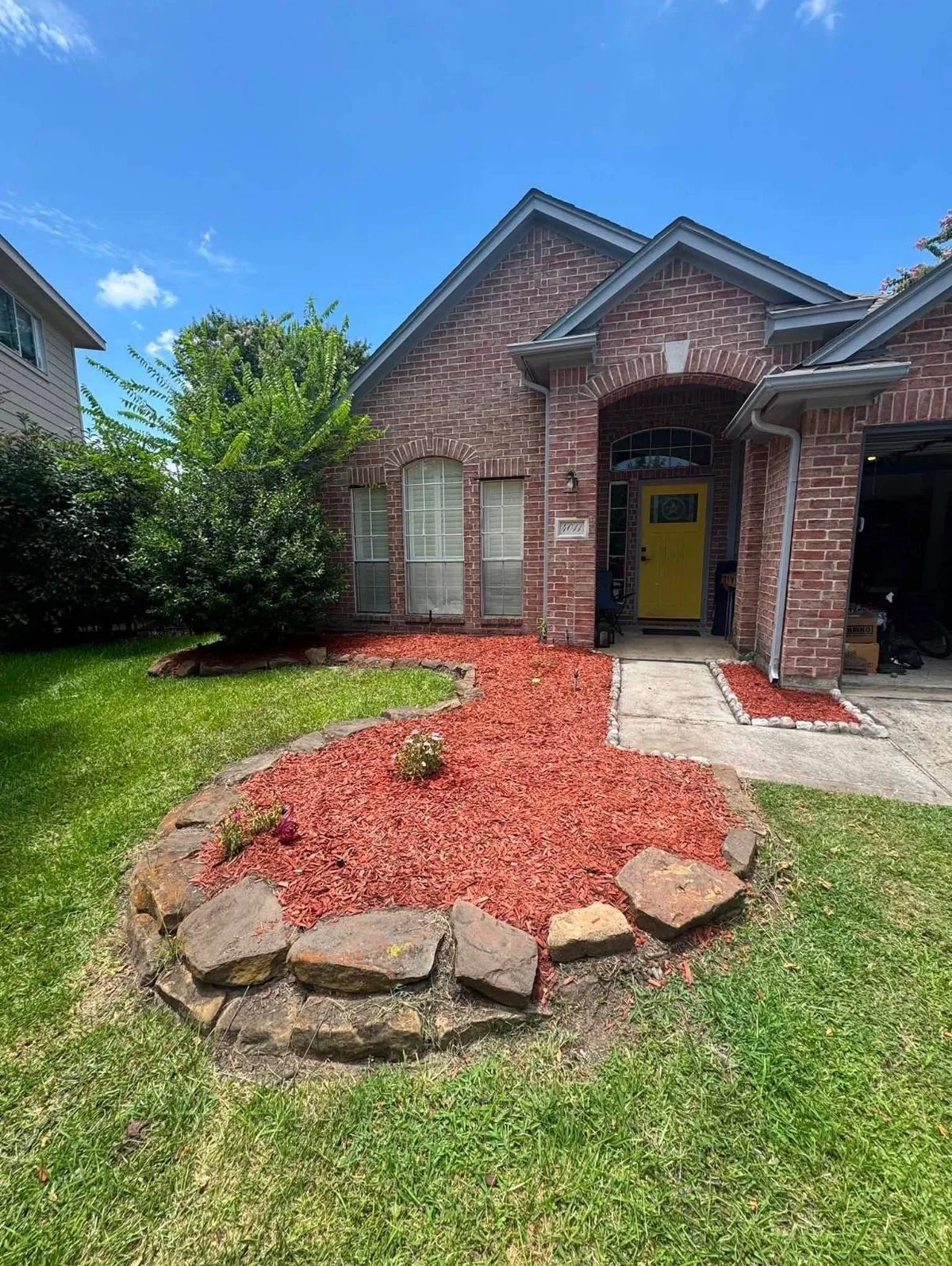 Curved rock border bed with fresh red mulch